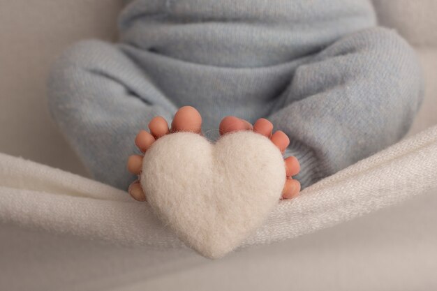 feet-newborn-baby-are-wrapped-knitted-blanket-fingers-newborn-baby-are-holding-white-knitted-heart-high-quality-photo_447871-358