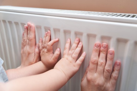 baby-hands-adult-feeling-radiator's-temperature-usually-440nw-12565323c